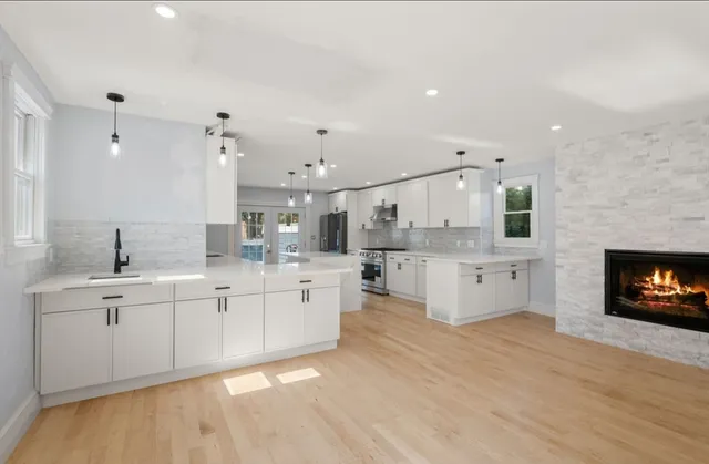 a large white kitchen with stainless steel appliances cabinets a island and a sink