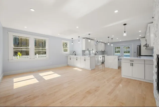 a view of an empty room with kitchen and window
