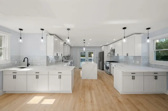 a large kitchen with stainless steel appliances kitchen island granite countertop a sink and cabinets