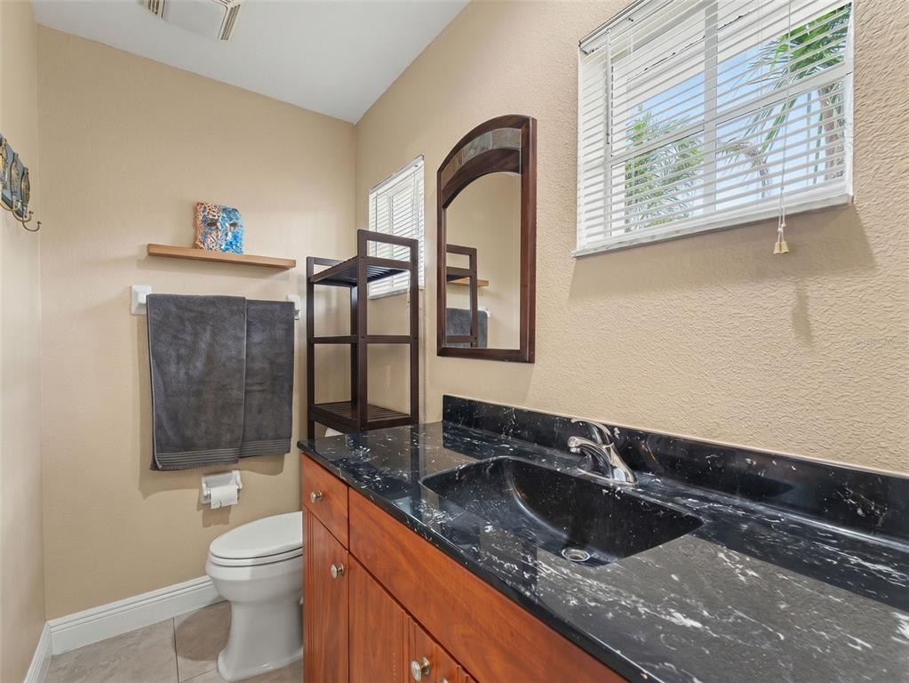 8910 Jericho Road Weeki Wachee, FL 34613 - Photo 11 of 52 a bathroom with a granite countertop sink a toilet and mirror
