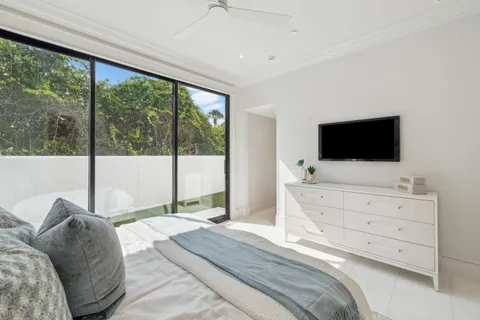 a bedroom with a large bed and a flat tv screen on dresser