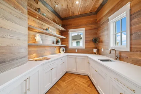 a large white kitchen with a sink and a large window