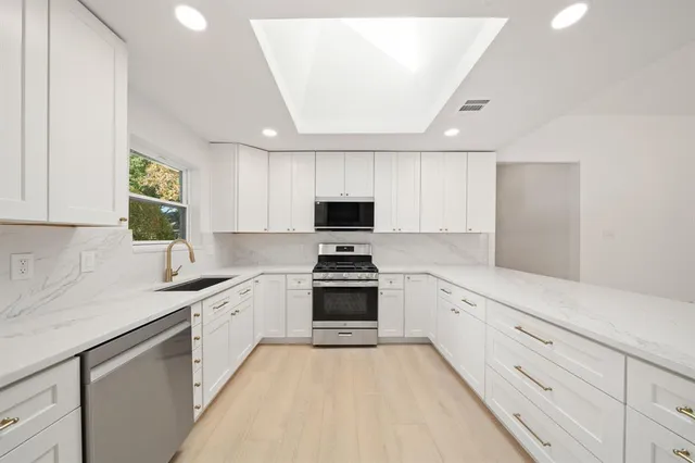 a kitchen with granite countertop a sink stainless steel appliances and cabinets