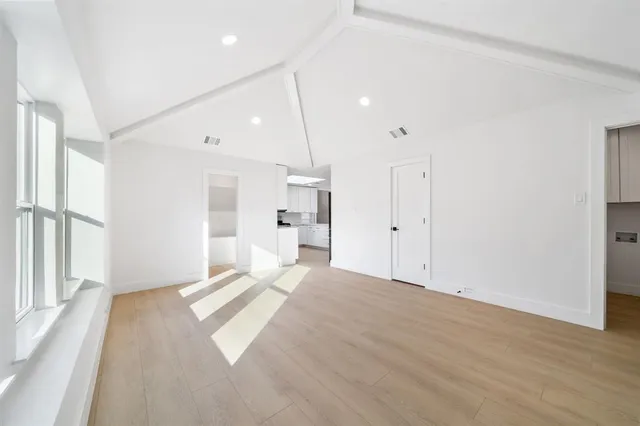 a view of empty room with wooden floor and windows