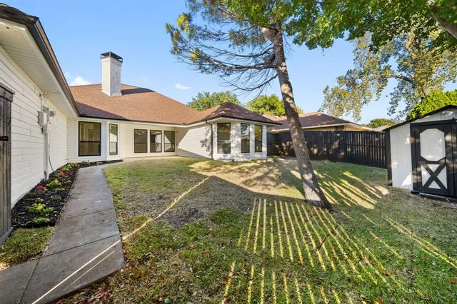 a view of a white house with a yard and table and chairs under an umbrella