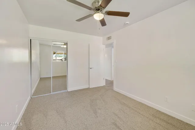 an empty room with a window and a fan