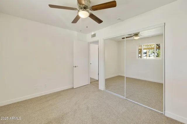 an empty room with a window and a fan