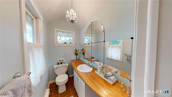 a bathroom with a granite countertop sink and mirror with toilet
