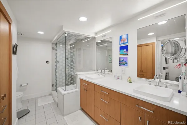 a bathroom with a double vanity sink toilet mirror and shower