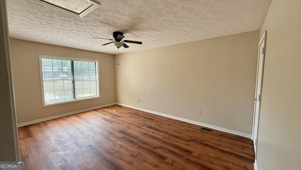 an empty room with windows and fan