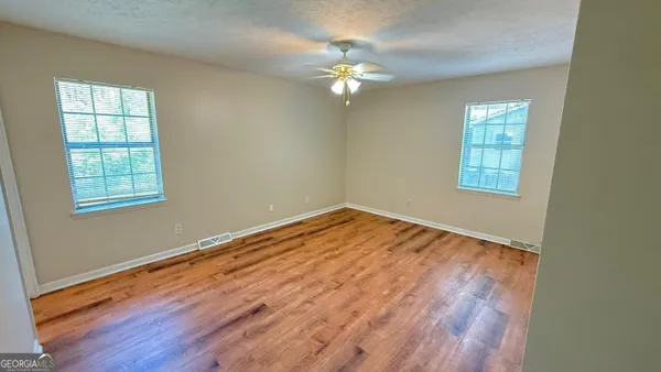 a view of empty room with wooden floor and fan