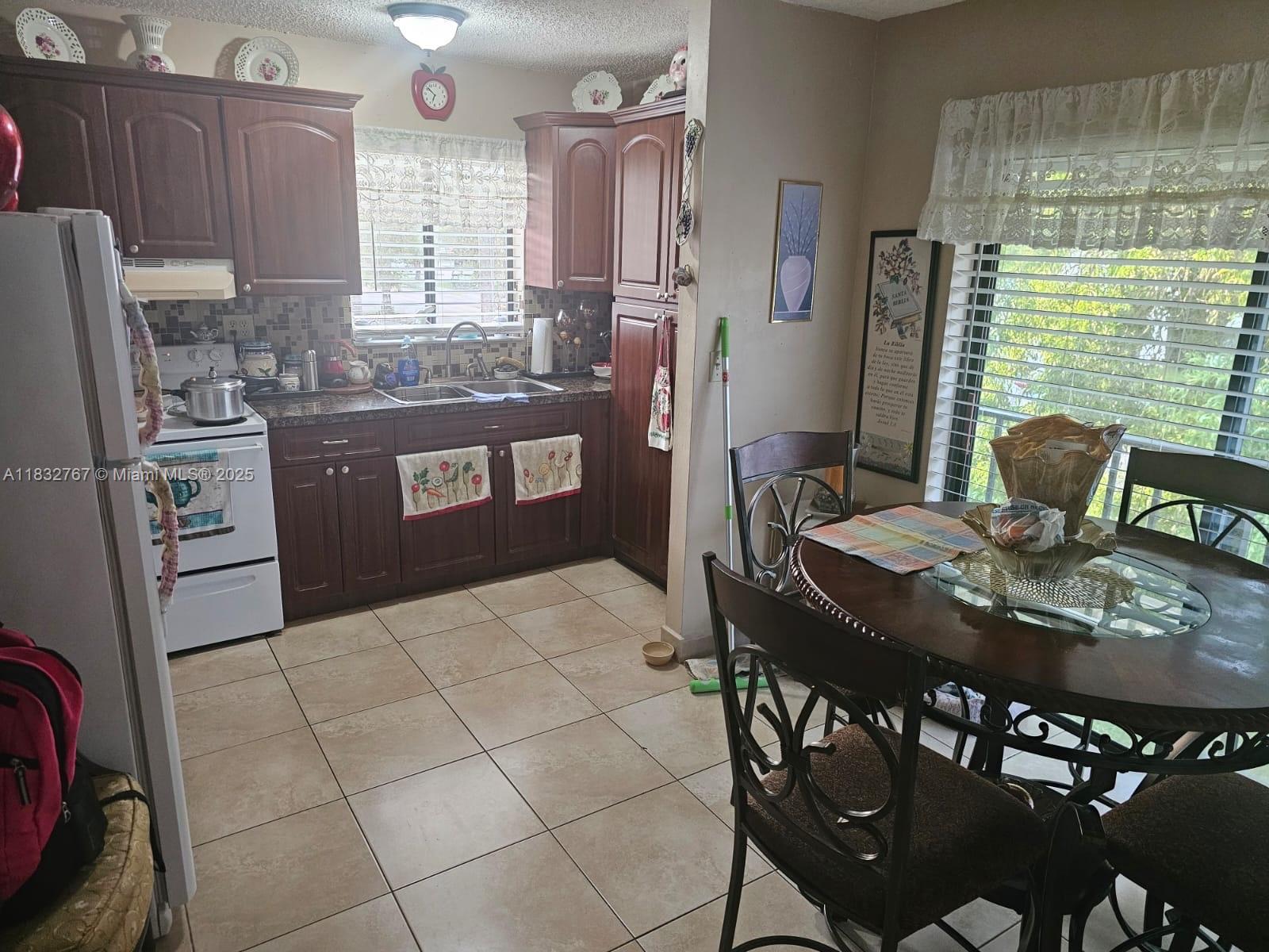 1521 West 42nd Place, Unit 18 Hialeah, FL 33012 - Photo 1 of 14 a kitchen with stainless steel appliances granite countertop a sink a stove a refrigerator a dining table and chairs