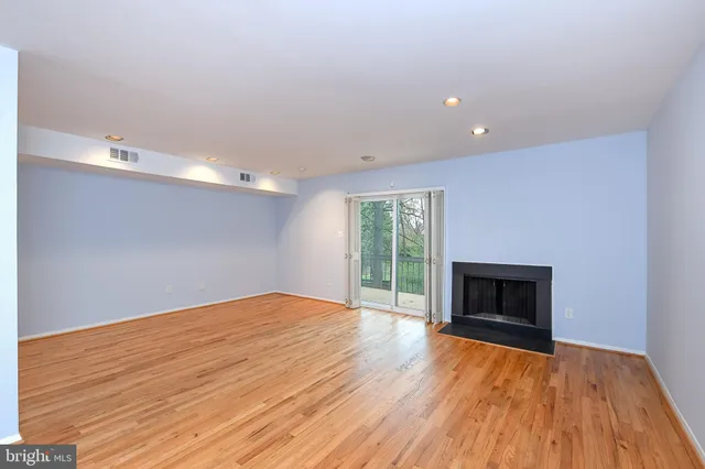a view of empty room with wooden floor and fireplace