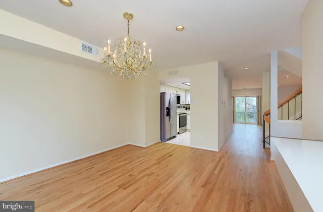 a view of a hallway with wooden floor and a chandelier