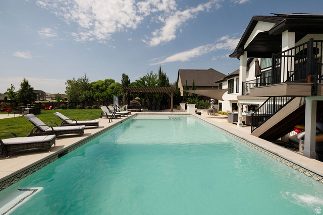 924 Country Lane Farmington, UT 84025 - Photo 83 of 91 Expansive backyard featuring a rectangular swimming pool with integrated steps, a surrounding light-toned paved patio, and a separate elevated deck with exterior stairs