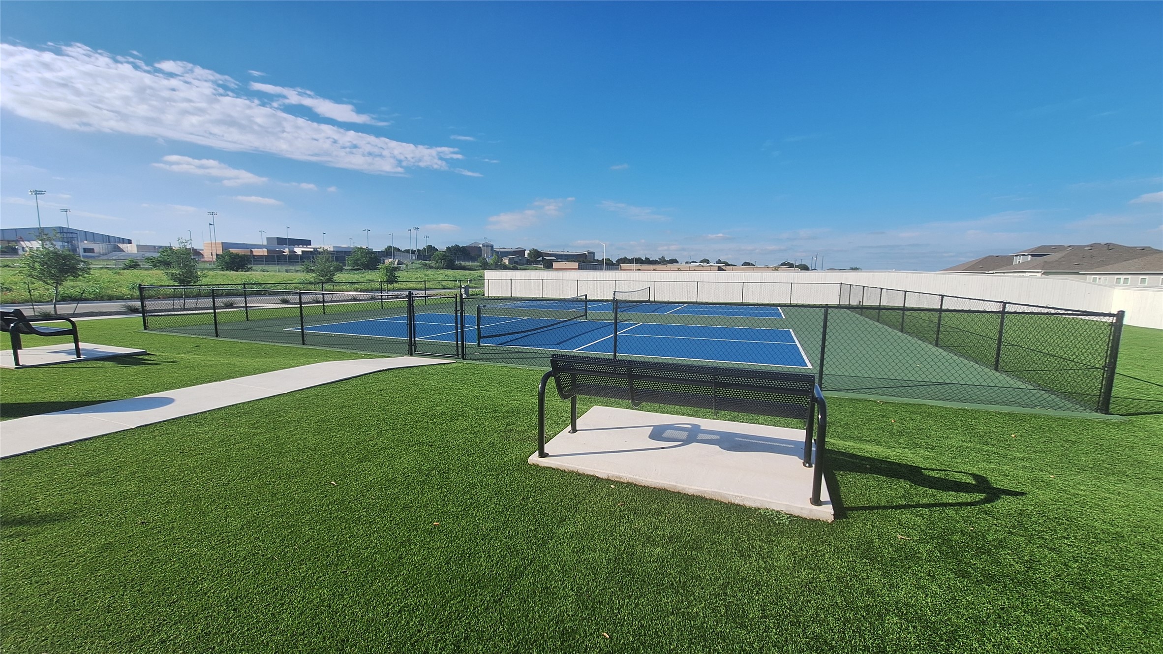 2771 Winding Creek Road Kyle, TX 78640 - Photo 22 of 24 Two blue courts, complete with nets and fencing, offer athletic leisure amidst green surroundings.