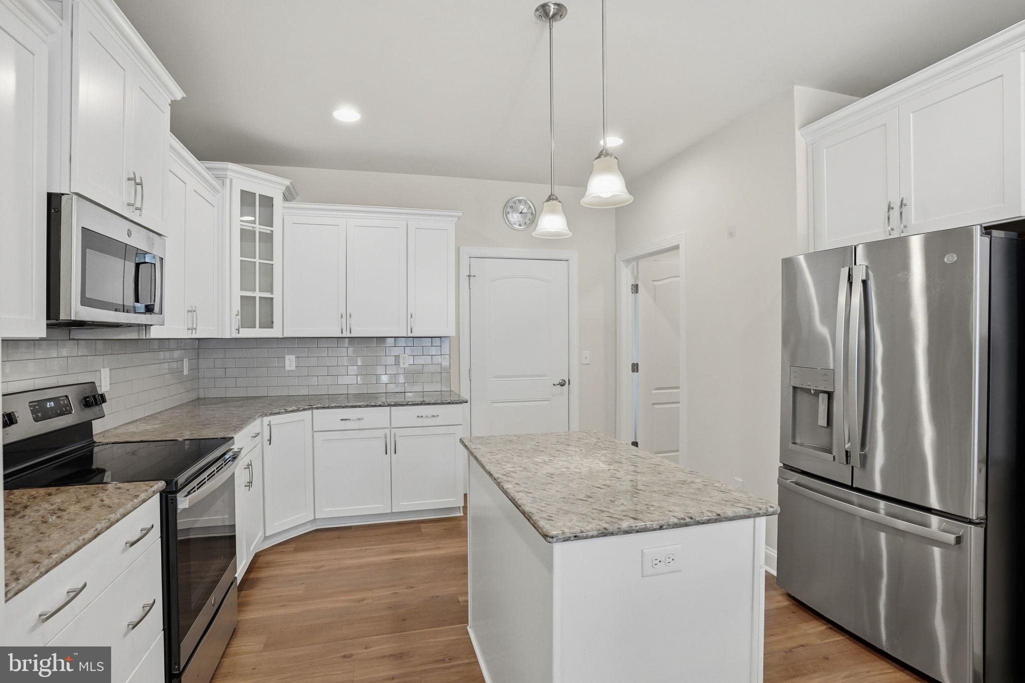 18822 Melville Way Georgetown, DE 19947 - Photo 3 of 24 a kitchen with stainless steel appliances granite countertop a refrigerator a sink dishwasher a stove and white cabinets with wooden floor