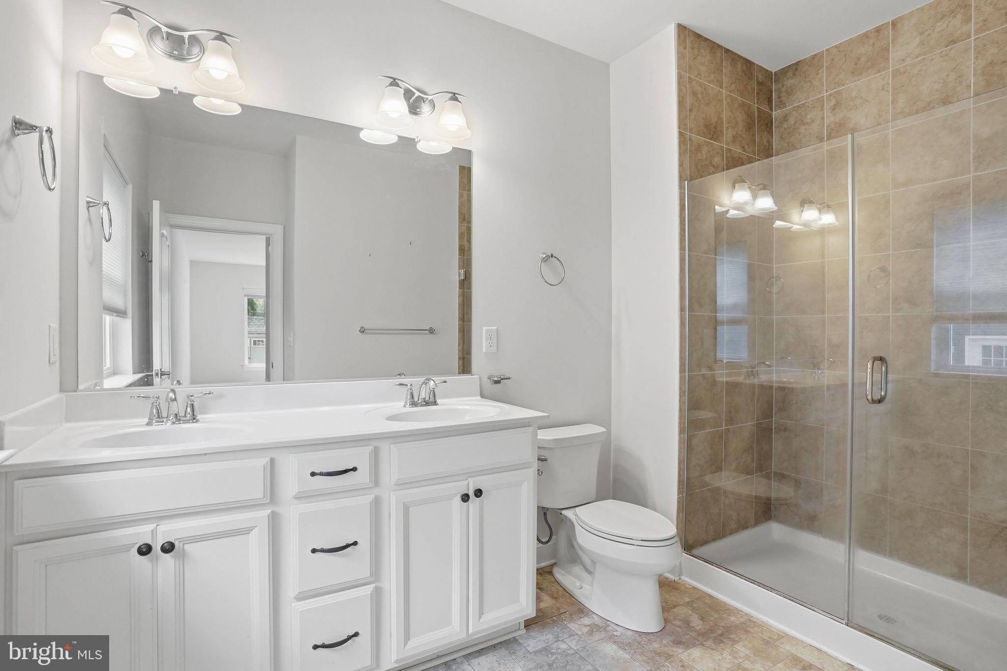 18822 Melville Way Georgetown, DE 19947 - Photo 7 of 24 a bathroom with a granite countertop sink toilet a large mirror a shower and vanity