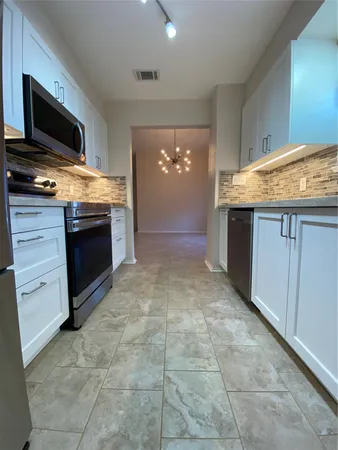 a view of living room kitchen with stainless steel appliances cabinets