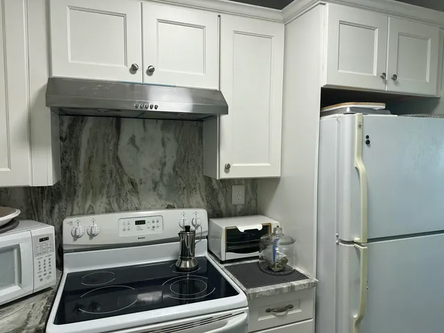 a kitchen with stainless steel appliances granite countertop a refrigerator and a stove top oven