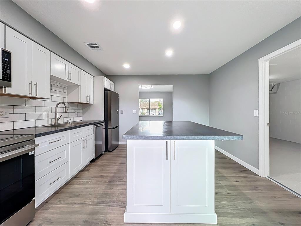 6848 Compass Court Orlando, FL 32810 - Photo 17 of 47 a kitchen with stainless steel appliances granite countertop a lot of counter space and wooden floors