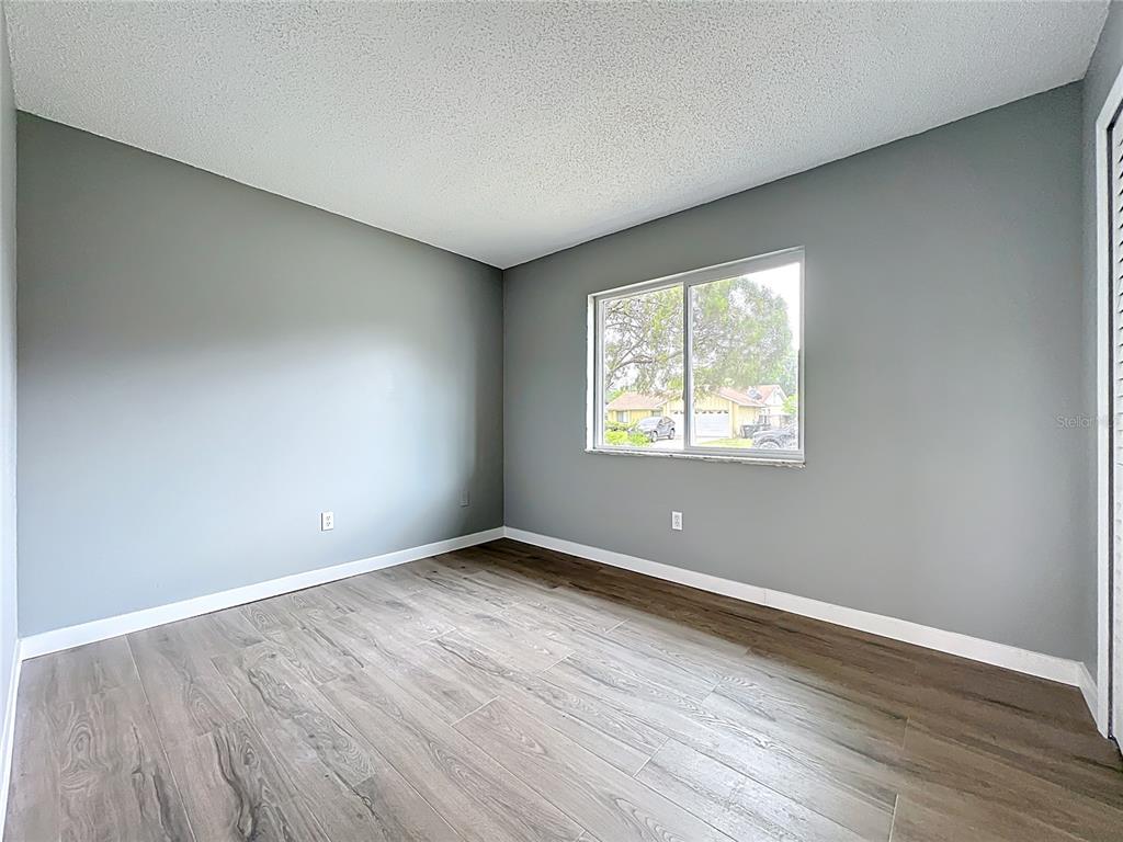 6848 Compass Court Orlando, FL 32810 - Photo 18 of 47 an empty room with wooden floor and windows