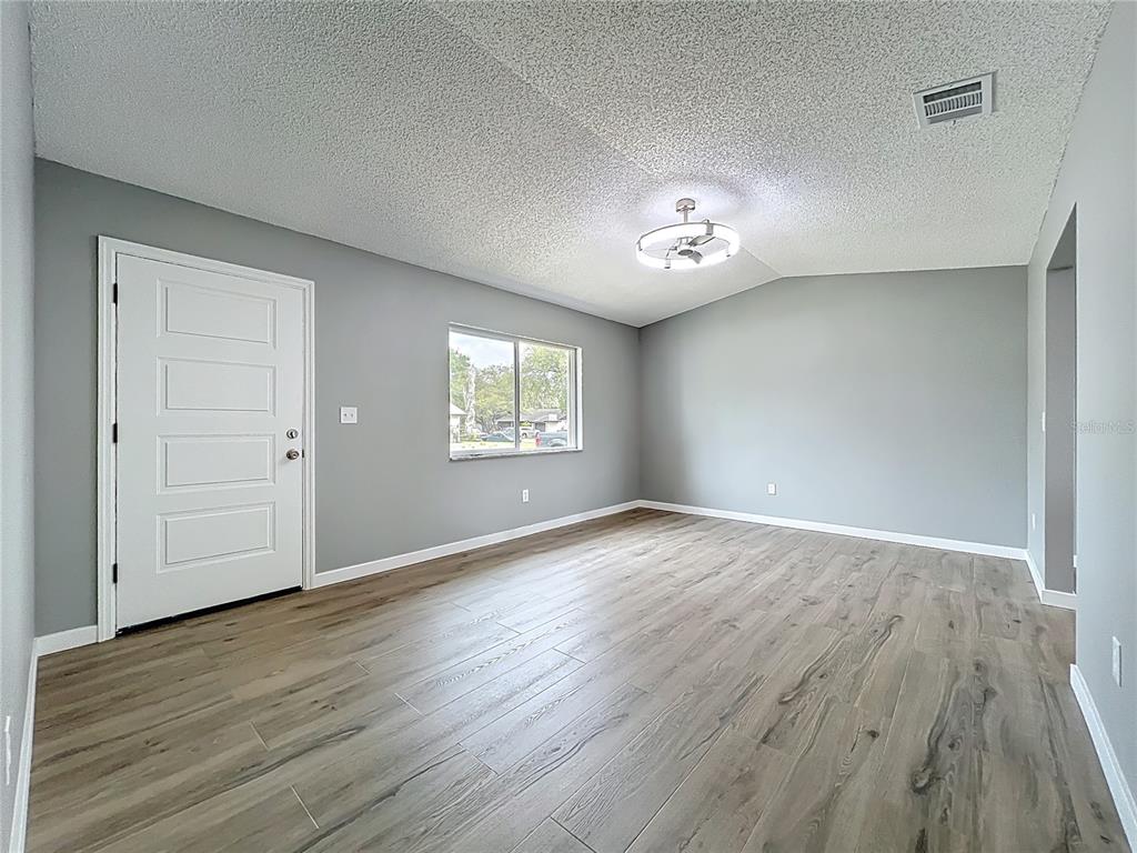 6848 Compass Court Orlando, FL 32810 - Photo 5 of 47 an empty room with wooden floor and windows