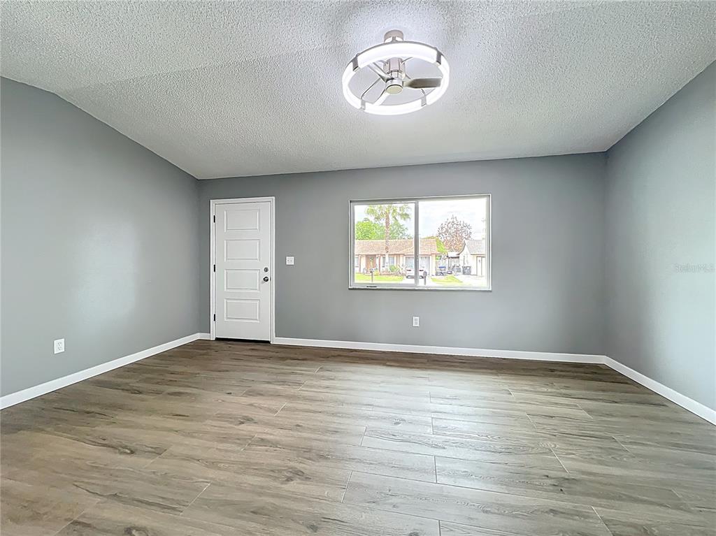 6848 Compass Court Orlando, FL 32810 - Photo 7 of 47 an empty room with wooden floor and windows