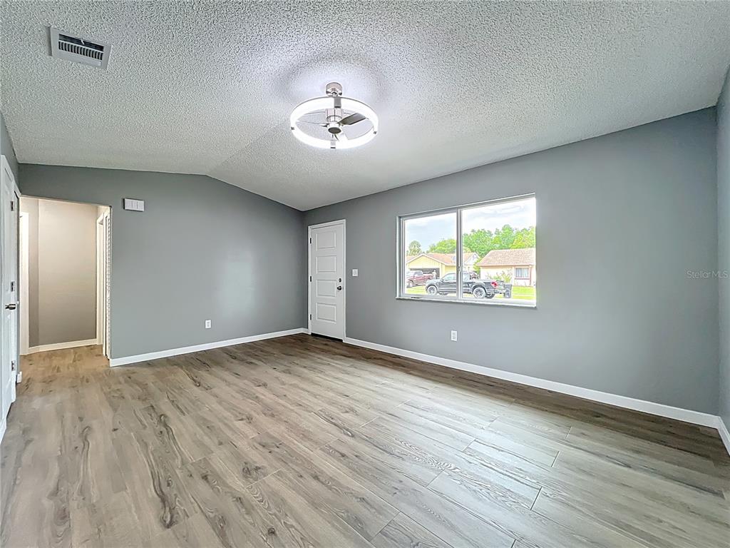 6848 Compass Court Orlando, FL 32810 - Photo 10 of 47 an empty room with wooden floor chandelier and windows