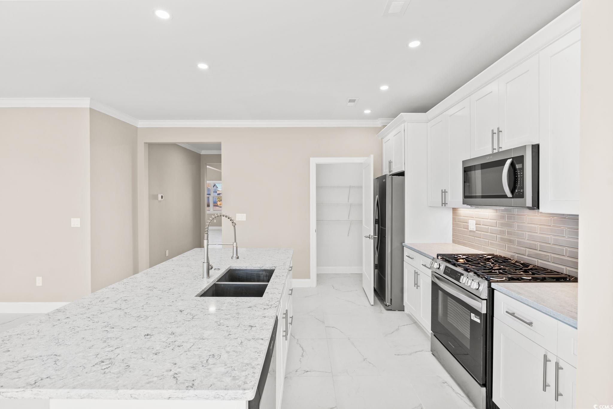600 Table Rock Court Myrtle Beach, SC 29579 - Photo 13 of 37 Kitchen with appliances with stainless steel finishes, a center island with sink, light marble finish flooring, white cabinetry, and recessed lighting