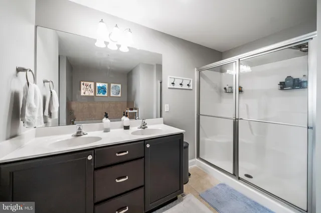 a bathroom with a double vanity sink mirror and shower