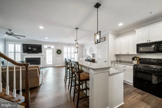 a kitchen with stainless steel appliances kitchen island granite countertop a stove a sink a refrigerator and chairs