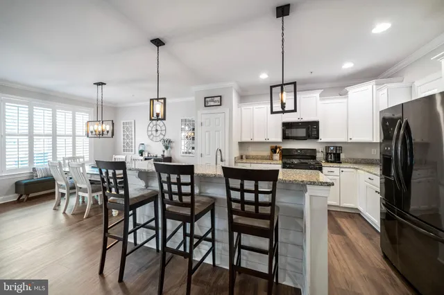 a kitchen with stainless steel appliances kitchen island granite countertop a dining table chairs stove refrigerator and microwave