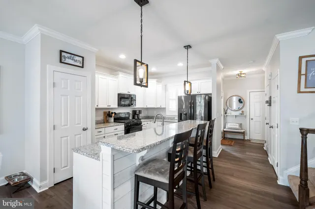 a kitchen with stainless steel appliances kitchen island granite countertop a refrigerator a stove a kitchen island with a dining table and chairs
