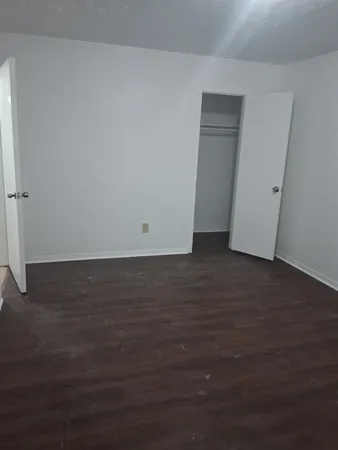 a view of an empty room with wooden floor and closet