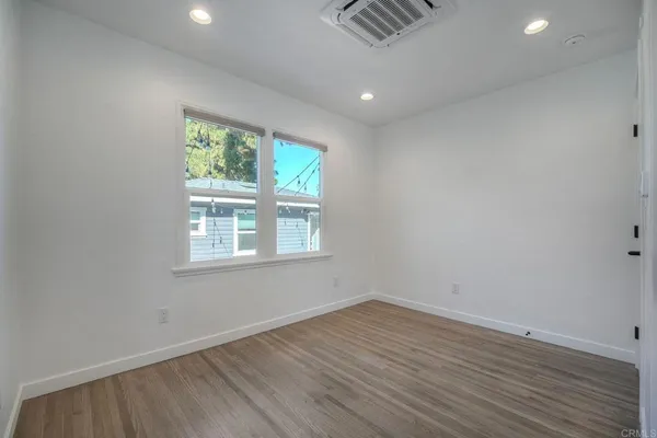 an empty room with wooden floor and windows