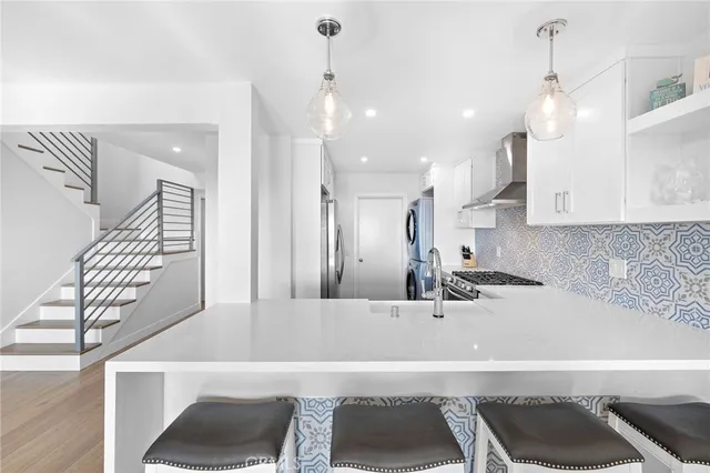 a view of a kitchen with kitchen island a sink wooden floor and a large window