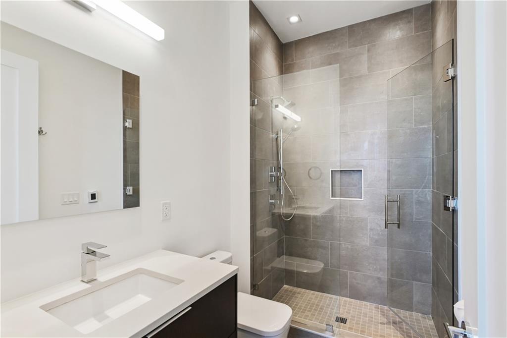 3107 Peachtree Road Northeast, Unit 2003 Atlanta, GA 30305 - Photo 42 of 114 a bathroom with a sink toilet a mirror and shower