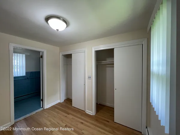 an empty room with wooden floor closet and windows