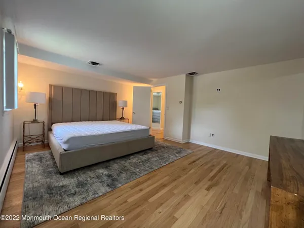 a spacious bedroom with a bed and wooden floor