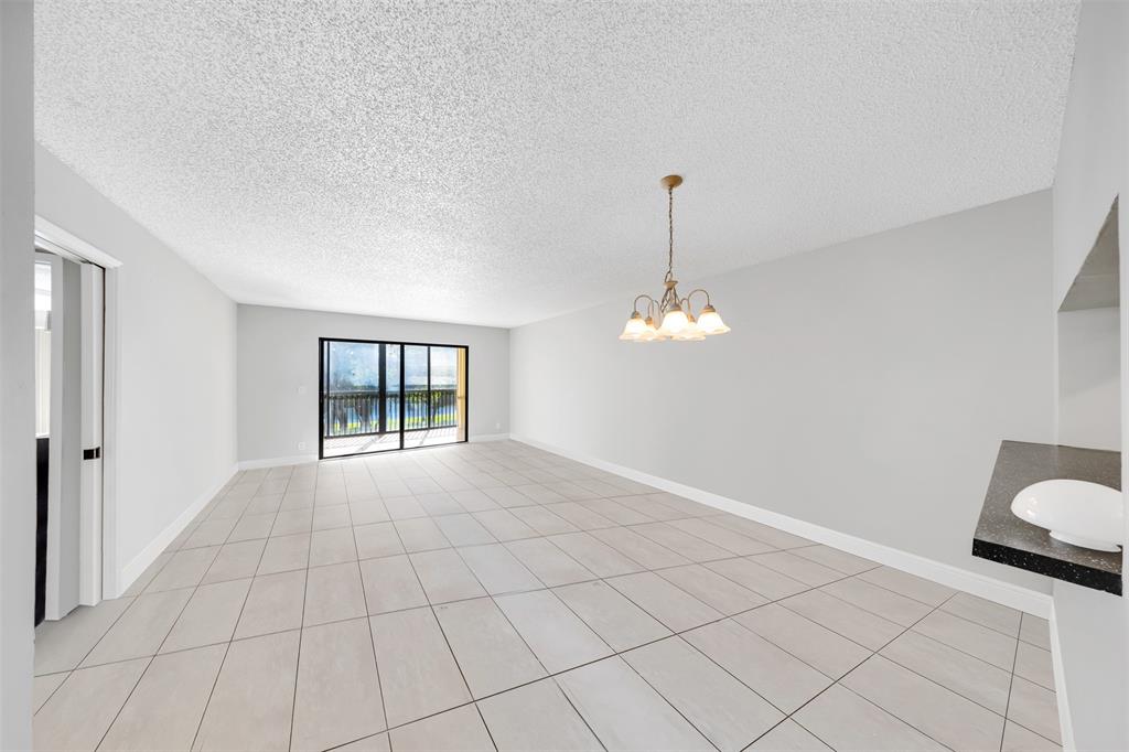 2202 South Cypress Bend Drive, Unit 207 Pompano Beach, FL 33069 - Photo 4 of 20 a view of an empty room with chandelier and window
