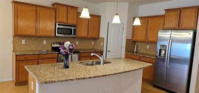 a kitchen with stainless steel appliances granite countertop a sink refrigerator and microwave