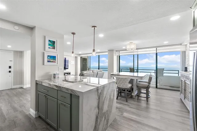 a dining hall with stainless steel appliances granite countertop a sink and chairs