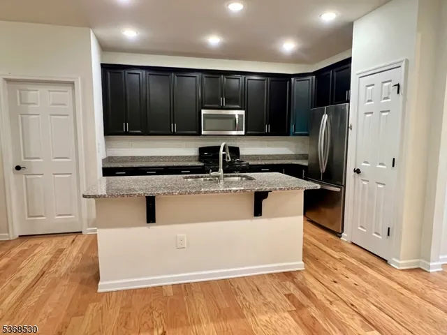 a view of kitchen with stainless steel appliances wooden floor and refrigerator