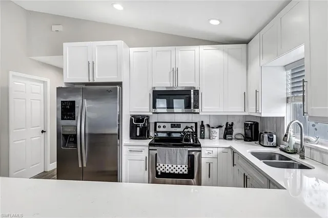 a kitchen with stainless steel appliances granite countertop a refrigerator a stove and a sink
