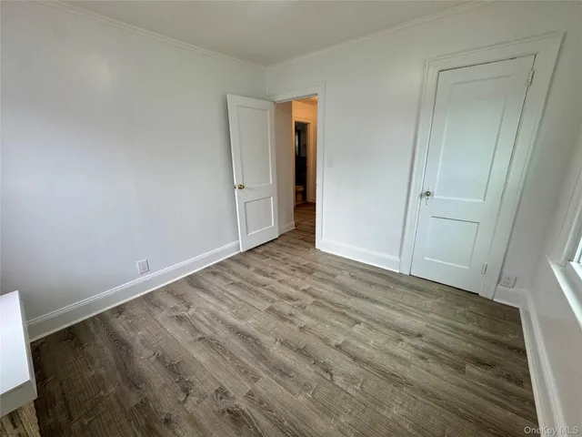 a view of an empty room with wooden floor and closet