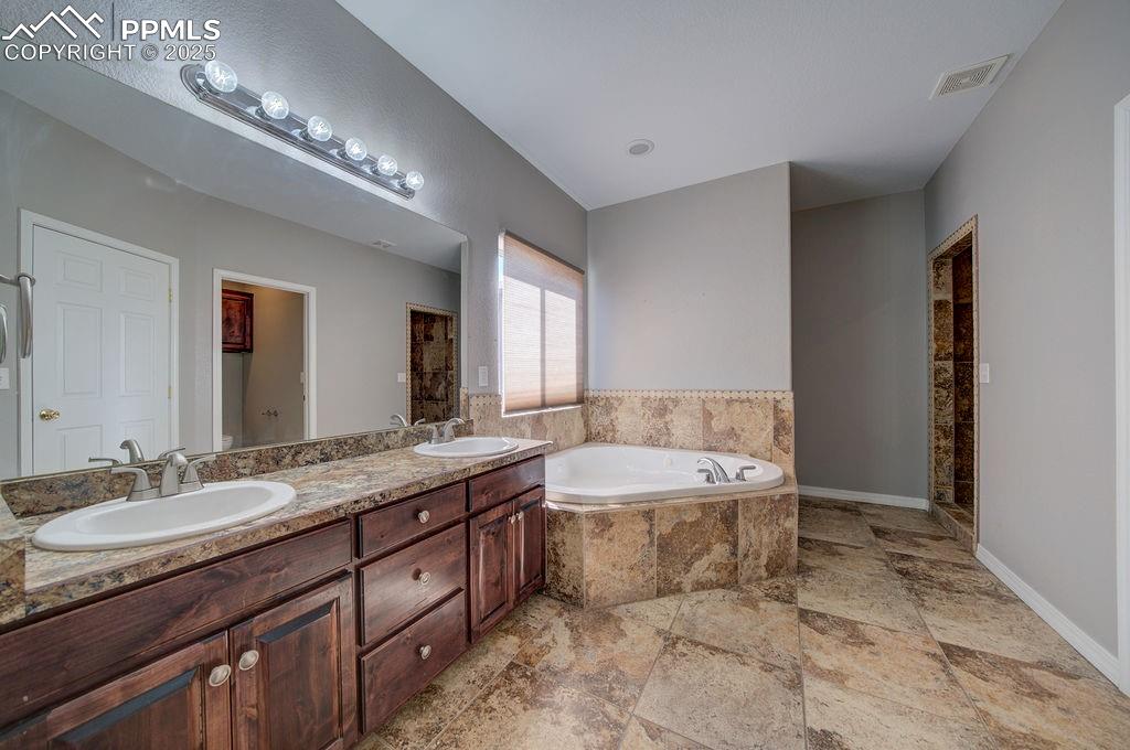 10935 McKissick Road Peyton, CO 80831 - Photo 42 of 50 a spacious bathroom with a granite countertop sink a toilet and a mirror