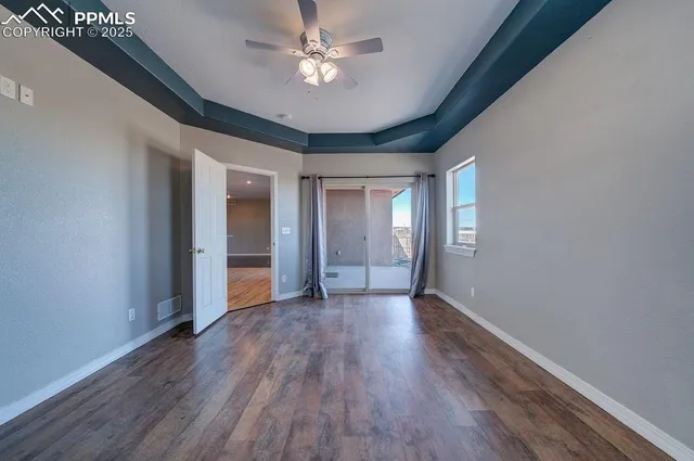 a view of an empty room with a window and wooden floor