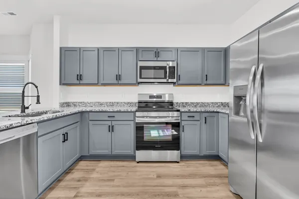 a kitchen with granite countertop a stove top oven and cabinets