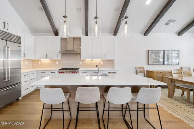 a kitchen with stainless steel appliances granite countertop a table chairs refrigerator and sink